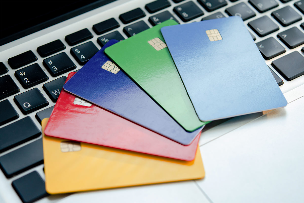 Yellow, red, dark blue, green, and light blue credit cards fanned out on a laptop keyboard.