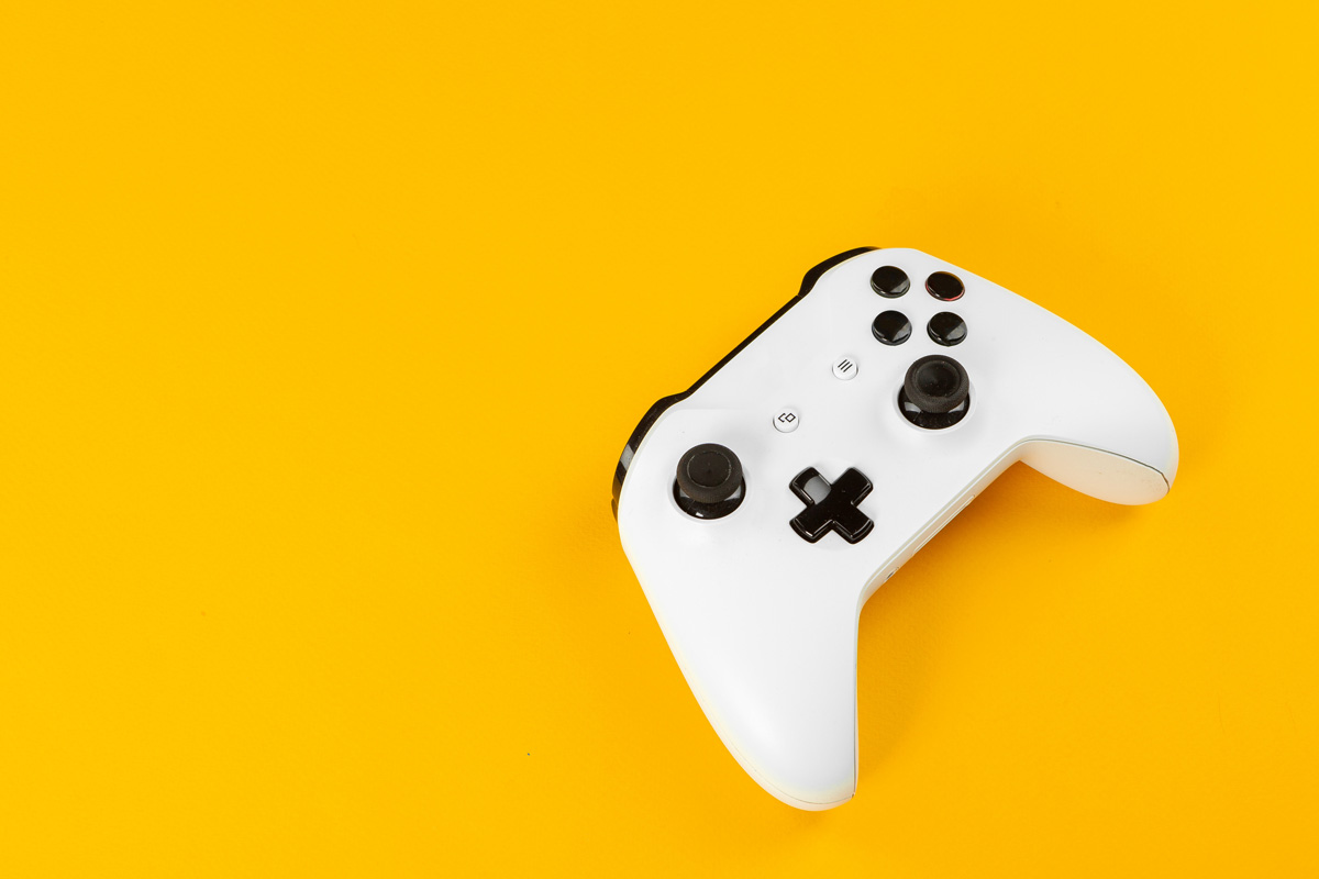 White game controller on a yellow background. 