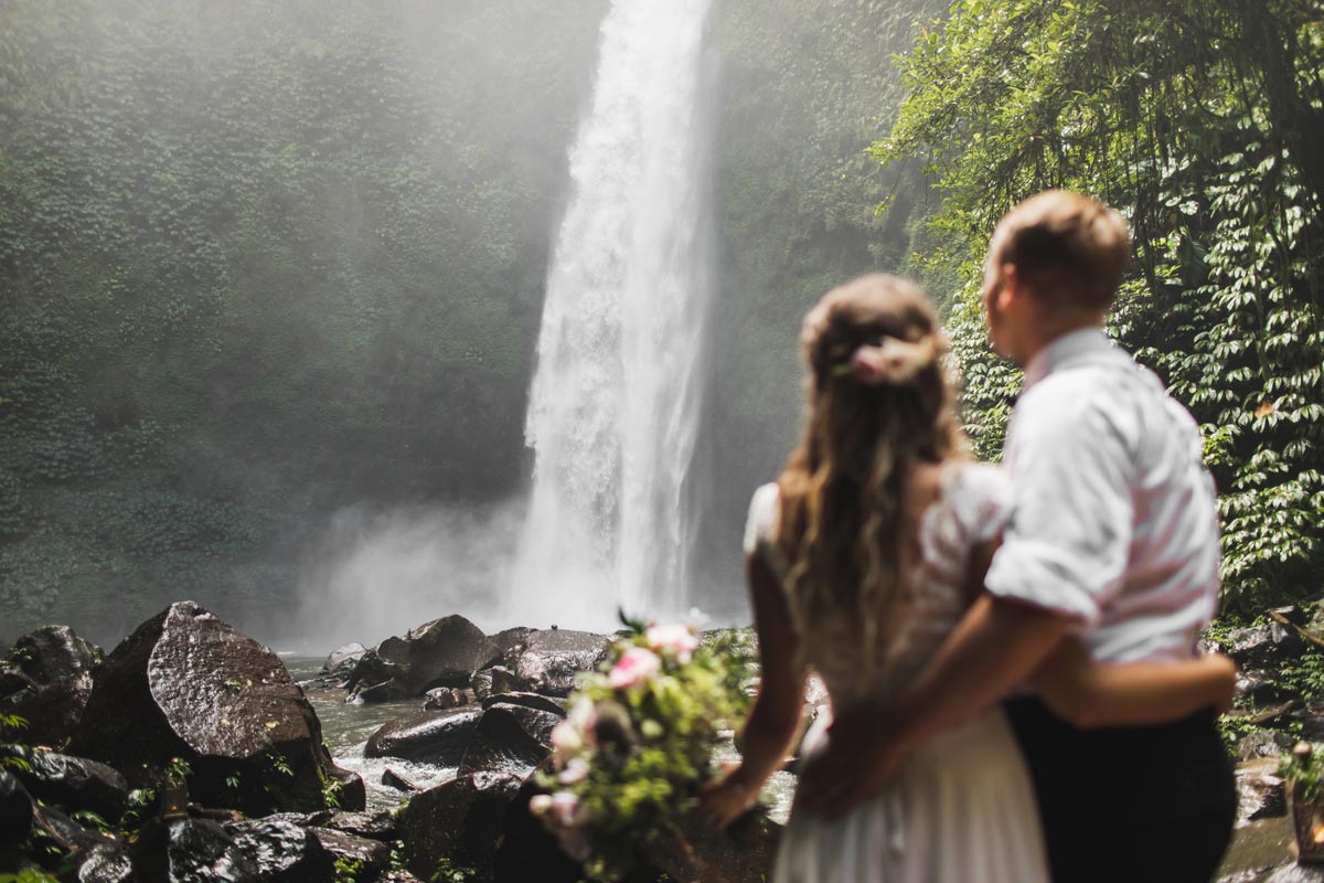 Wedding couple admiring a large waterfall in nature