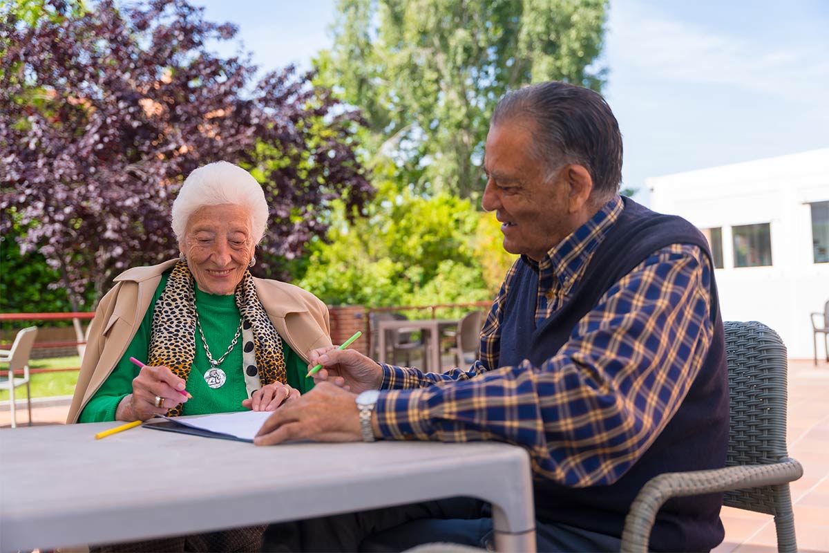 Elderly women and man ages 65-75 sitting outside writing a birthday card