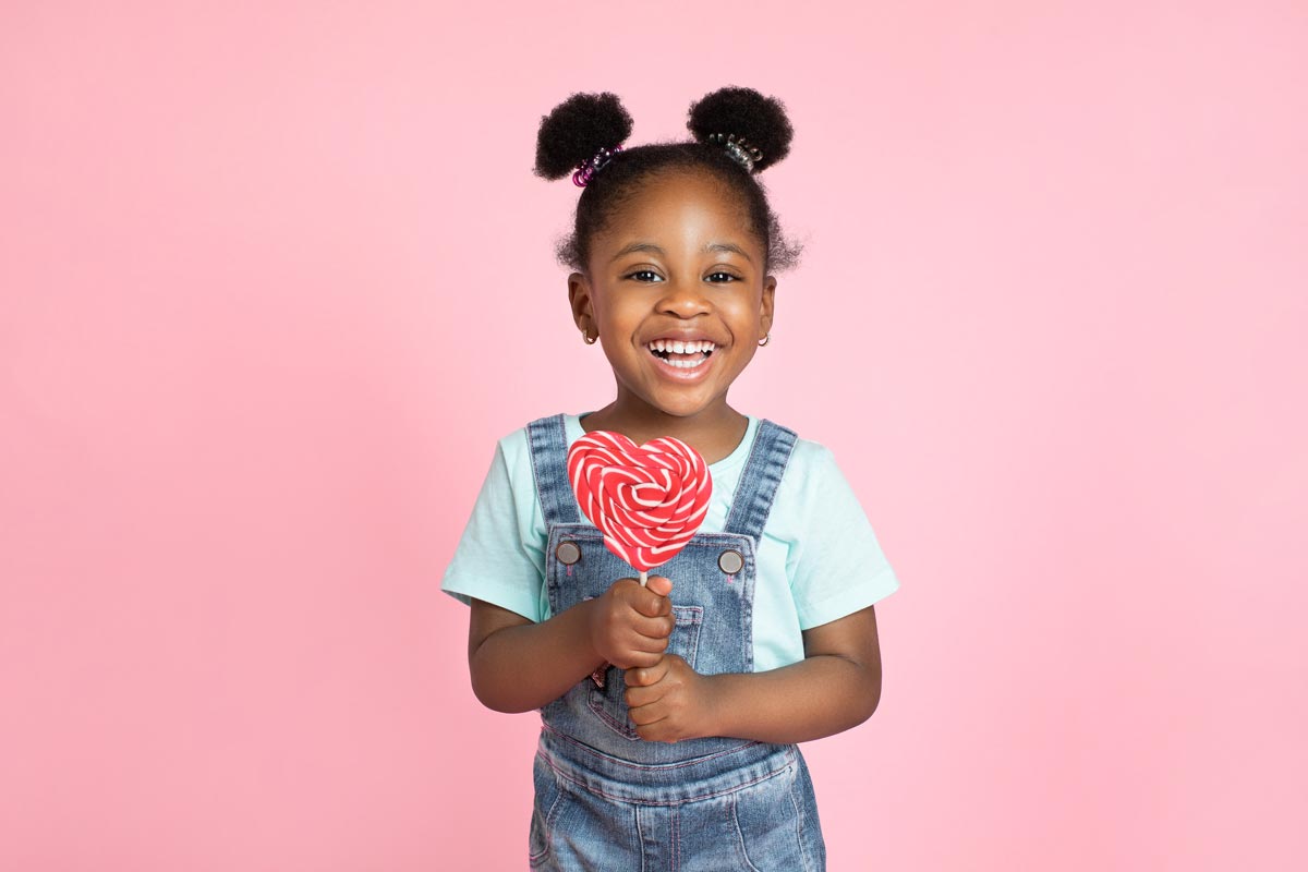  Little black girl smiling holding a lollipop 