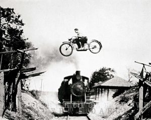 An image of a motorcycle jumping train freestyle motocross extreme sports vintage photo print poster daredevil biker gift wall decor black and white art